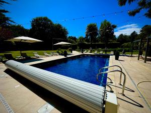 a swimming pool in a park with chairs and umbrellas at La Mancha Hall Stately Home in Halsall