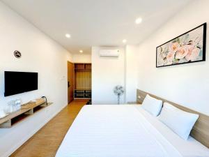 a bedroom with a large white bed and a flat screen tv at Ruby Homestay in Cam Lâm