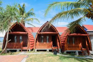 two thatched cottages with palm trees in front of them at vila La-surf in Padangnegeri