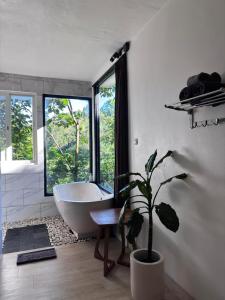 a bathroom with a tub and a potted plant at Gumi Ayu EcoStay in Munduk