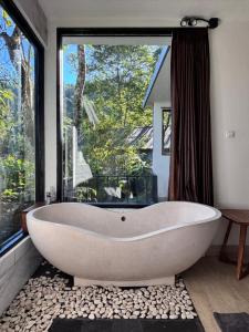 a bath tub in a bathroom with a large window at Gumi Ayu EcoStay in Munduk
