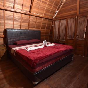 a bedroom with a bed in a wooden room at vila La-surf in Padangnegeri