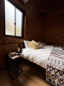 a bed in a wooden room with a window at Retreat 舞月 in Tanabe