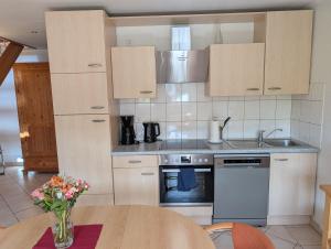 a kitchen with wooden cabinets and a table with flowers at Am Weinberg in Bernkastel-Kues