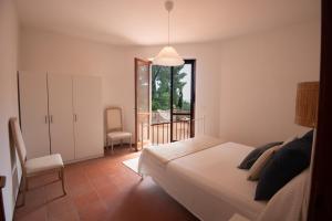 a bedroom with a bed and a chair and a window at Villa Fornaci - Marina di Campo in Marina di Campo