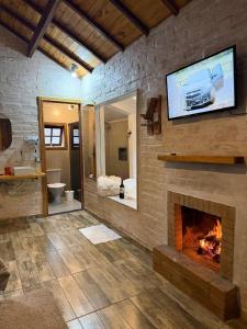 a bathroom with a fireplace with a tv above it at Chalé Recanto dos Pinheiros in Monte Verde