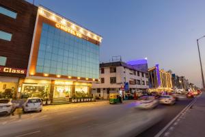 a city street with cars driving past a glass building at Arch The Venus - Free Airport Pickup or Drop in New Delhi