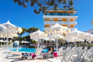 een hotel met stoelen en parasols voor een zwembad bij Hotel Alexander in Caorle