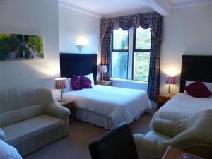 a hotel room with two beds and a couch and a window at Ilkley Riverside Hotel in Ilkley