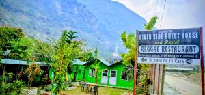 a sign in front of a green house with a building at Riverside guest house in Besisahar