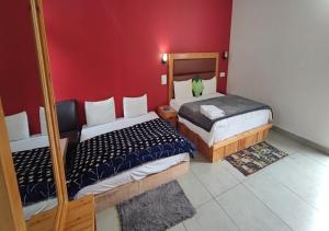 two beds in a room with a red wall at Woodward 2 by 4 Wildflower in Kasol