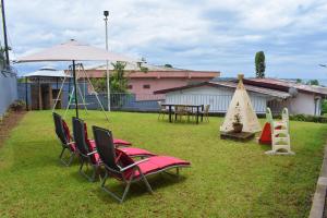 a yard with chairs and an umbrella and a playground at Villa les 3 oisillons in Kribi