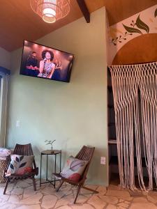 a living room with two chairs and a tv on the wall at Chalé da árvore Buzios in Búzios
