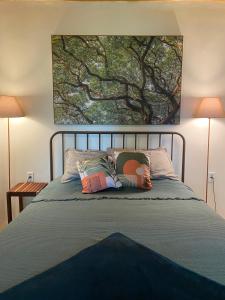 a bed with two pillows and a painting on the wall at Chalé da árvore Buzios in Búzios