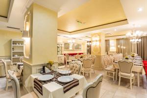 un comedor con mesas y sillas blancas en Rena Hotel - All Inclusive, en Sunny Beach