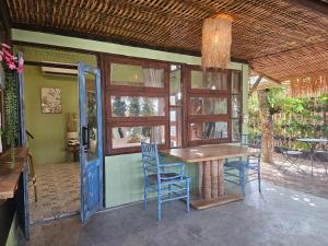 a dining room with a wooden table and blue chairs at Three Hen Lakeside in Ban Na Nai