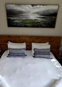 a white bed with two pillows and a painting on the wall at The Loft in Mtunzini