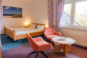 a bedroom with a bed and two chairs and a table at Pension Herkules in Koserow