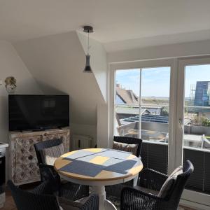 a dining room with a table and chairs and a television at Kastanienhüs Apartment in Westerland