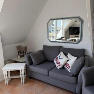 a living room with a gray couch and a mirror at Kastanienhüs Apartment in Westerland