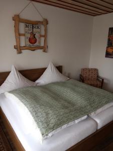 a bedroom with a bed with a green comforter at Pension Ochsen, Gästezimmer in Unadingen in Löffingen +1 photo