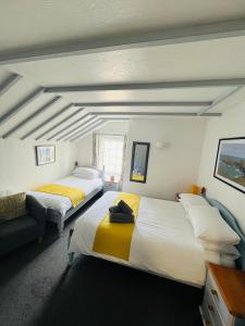 two beds in a room with white and yellow at The Fourways Inn in Saint Minver