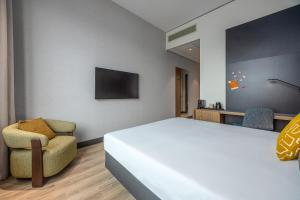 a bedroom with a large white bed and a chair at Postillion Hotel Breda Biesbosch in Raamsdonksveer