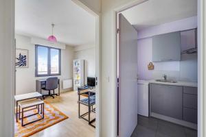 a kitchen with white cabinets and a table in a room at Spacious Studio 2P - Near La Défense in Courbevoie