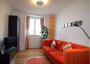 a living room with an orange couch and a television at Estrela Cozy Apartment in Lisbon