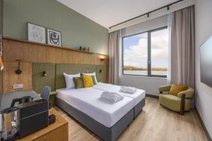 a hotel room with a bed and a tv and a window at Postillion Hotel Breda Biesbosch in Raamsdonksveer +32 photos