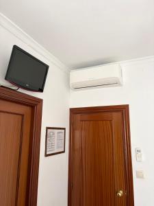 a room with a tv on the wall next to two doors at Hidalgo in Alcaudete