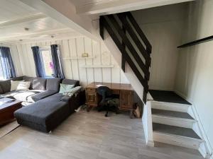 a living room with a couch and a desk at Snemyr i Høvåg in Høvåg