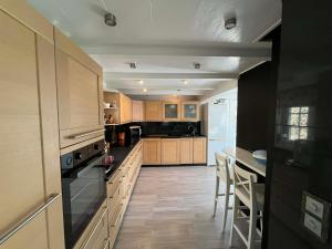 a large kitchen with wooden cabinets and a counter top at Snemyr i Høvåg in Høvåg