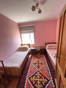 two beds in a room with pink walls and a rug at Tumar guest house, Kochkor in Kochkorka