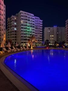 a large pool with blue lights in a city at night at Pool View Studio Apartment Caesar Resort & Spa in Dherinia