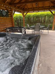 a hot tub in a patio with a table and chairs at Zso-Zé Apartman in Tiszafüred
