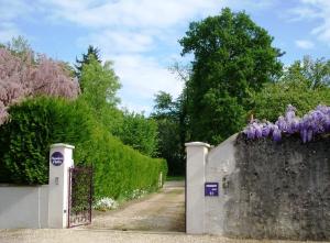 a gate with purple flowers on top of it at La Renaissance Saint-Gervais-la-Forêt in Saint-Gervais-la-Forêt