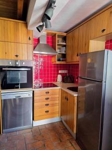 a kitchen with wooden cabinets and a stainless steel refrigerator at Casa Pedra da Foz in Odeceixe