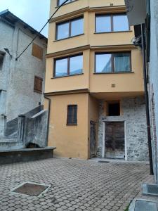 a yellow building with windows on a brick street at Alloggio valle stura in Vinadio +3 photos