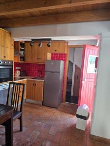 a kitchen with a refrigerator and a red door at Casa Pedra da Foz in Odeceixe