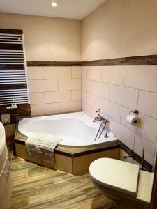 a bathroom with a bath tub and a toilet at FeWo Am Feldrand in Prebberede