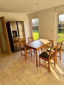 a dining room with a table and chairs and a refrigerator at FeWo Am Feldrand in Prebberede