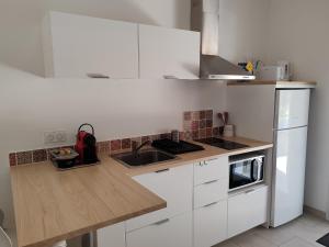 a kitchen with white cabinets and a wooden counter top at Au Cabanon in Saint-Laurent-dʼAigouze