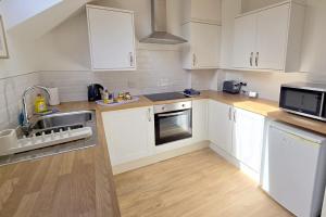 a kitchen with white cabinets and a sink at Phoenix Cottage, Bakewell in Bakewell