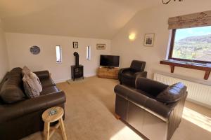 a living room with two leather couches and a television at Phoenix Cottage, Bakewell in Bakewell