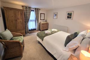 a bedroom with a large bed and a chair at Phoenix Cottage, Bakewell in Bakewell