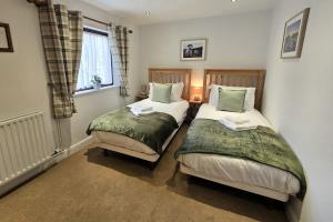 two beds in a small room with a window at Phoenix Cottage, Bakewell in Bakewell +3 photos