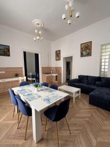 a living room with a white table and blue chairs at Katerina Apartman in Gyula