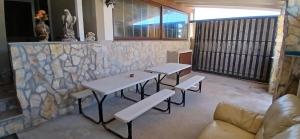 two tables and benches in a room with a stone wall at Lampedusa da Sogno 1 in Lampedusa