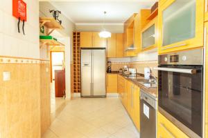 a kitchen with wooden cabinets and a stainless steel refrigerator at Villa Solara - com piscina aquecível e BBQ em Carvoeiro in Carvoeiro